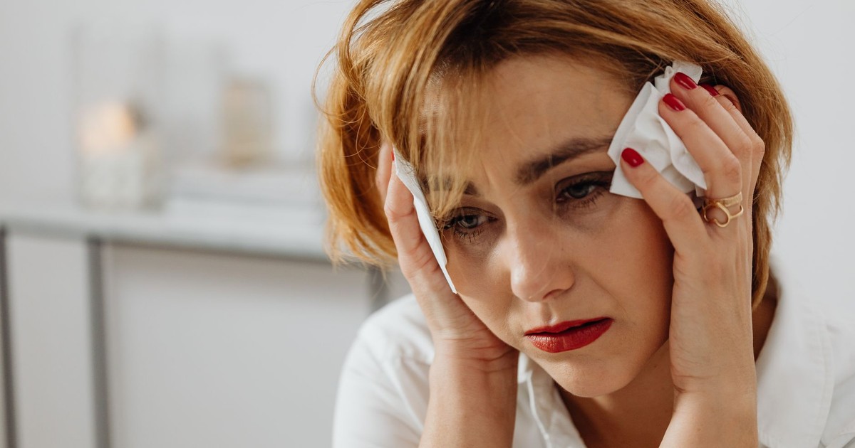 Close-up of a woman in distress holding tissues, expressing emotional sadness.