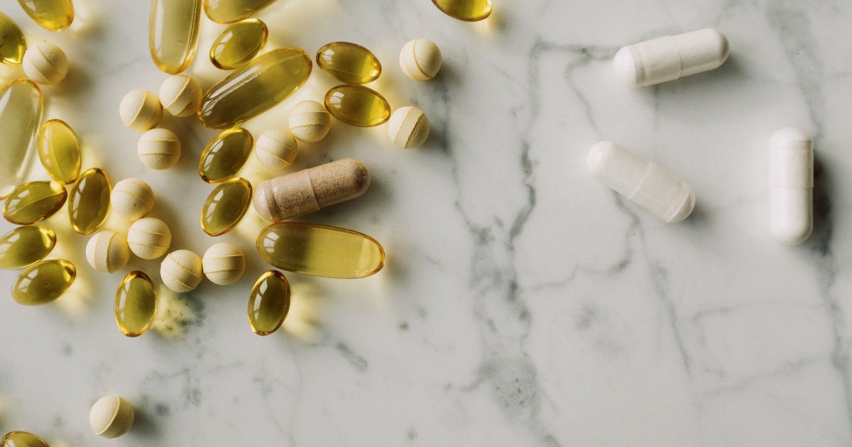 A variety of capsules and pills scattered on a marble surface, offering a modern healthcare concept.