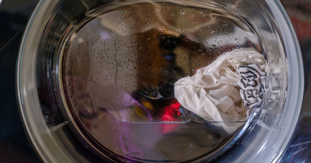 A clear view of wet clothes spinning inside a front-loading washing machine.