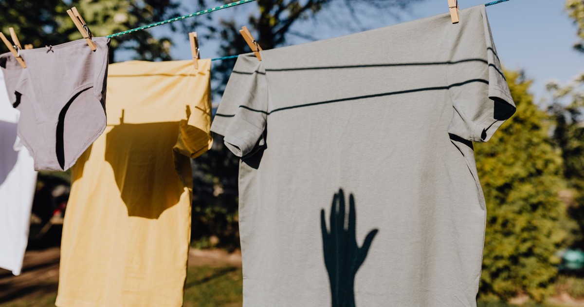 Clean washed clothes hanging on rope with clothespins outdoors on sunny summer weather