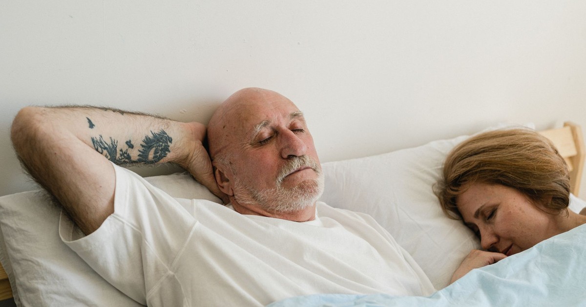 Peaceful elderly couple sleeping together in bed, showing relaxation and comfort.