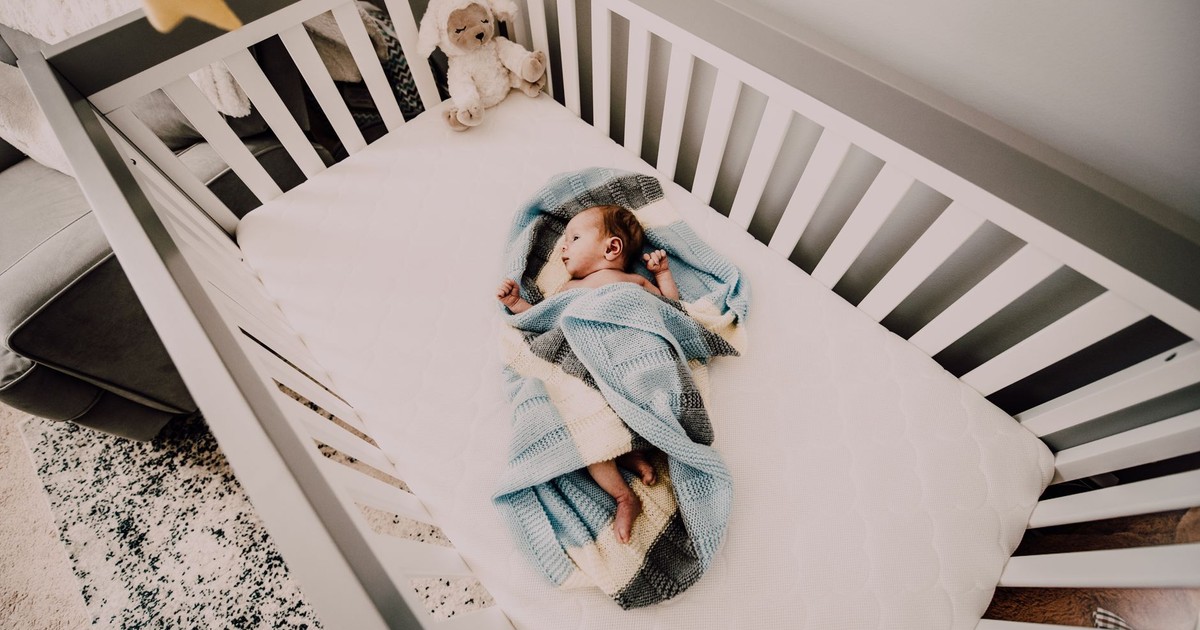 A peaceful baby wrapped in a blanket sleeps in a cozy crib, creating a serene nursery atmosphere.