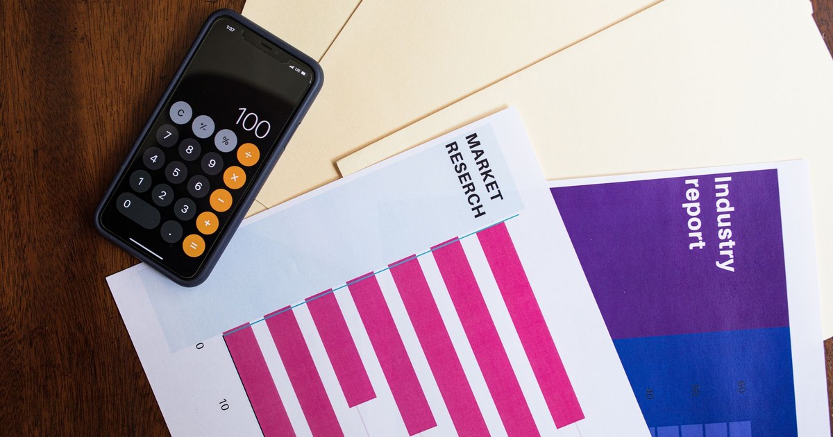 Flat lay of smartphone and market research papers on wooden table for business analysis.