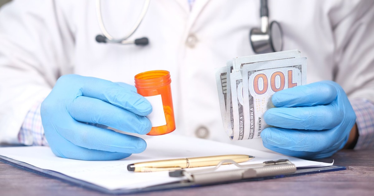 Doctor in gloves holding pill bottle and cash, highlighting medical expenses.