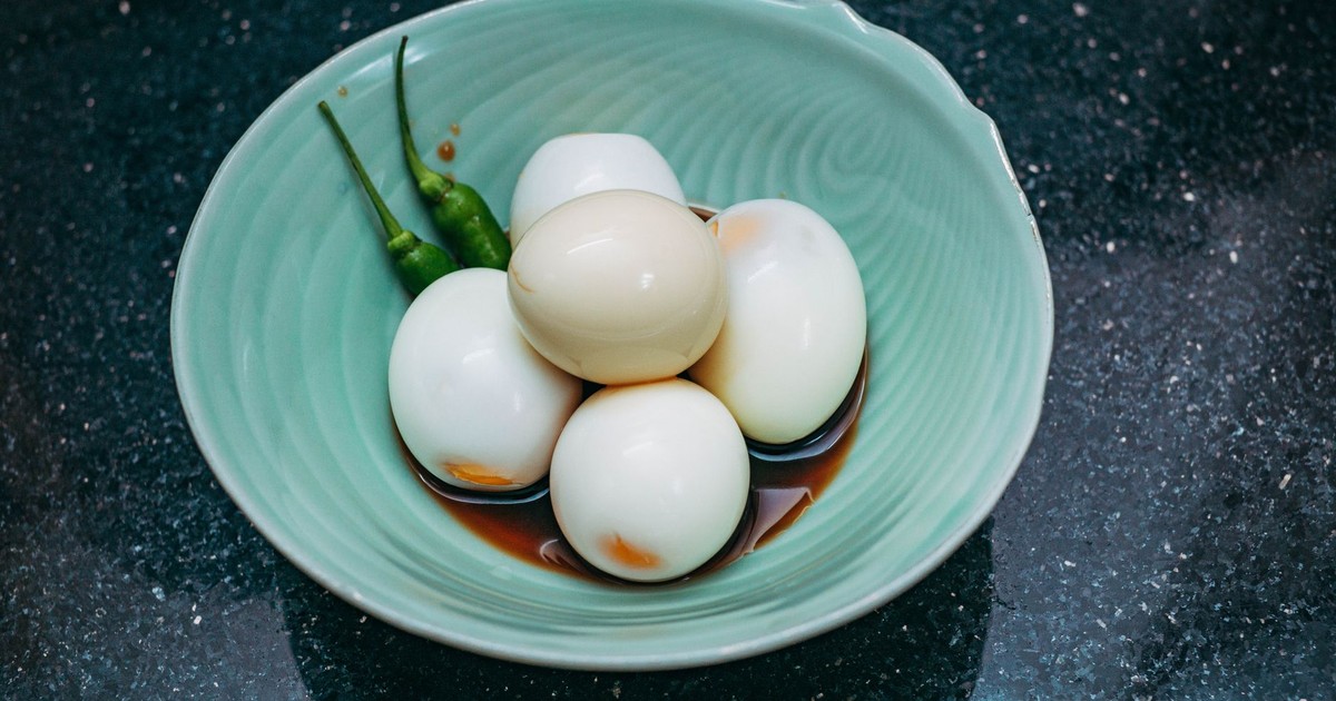 A bowl of boiled eggs with green chilies and soy sauce, perfect for a savory snack.