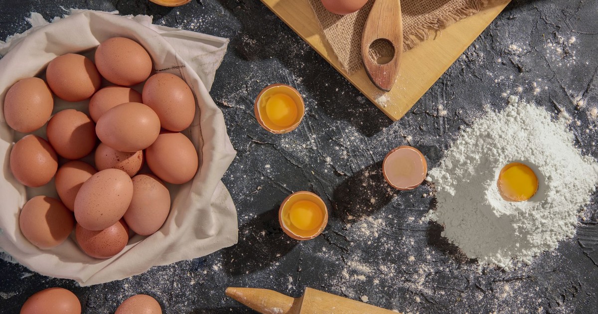 Flat lay of eggs, flour, and kitchen tools for baking preparation.