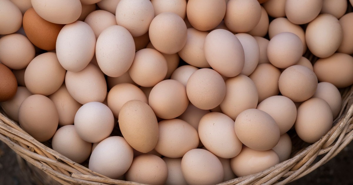 A heap of fresh brown and white eggs in a wicker basket, captured from above.