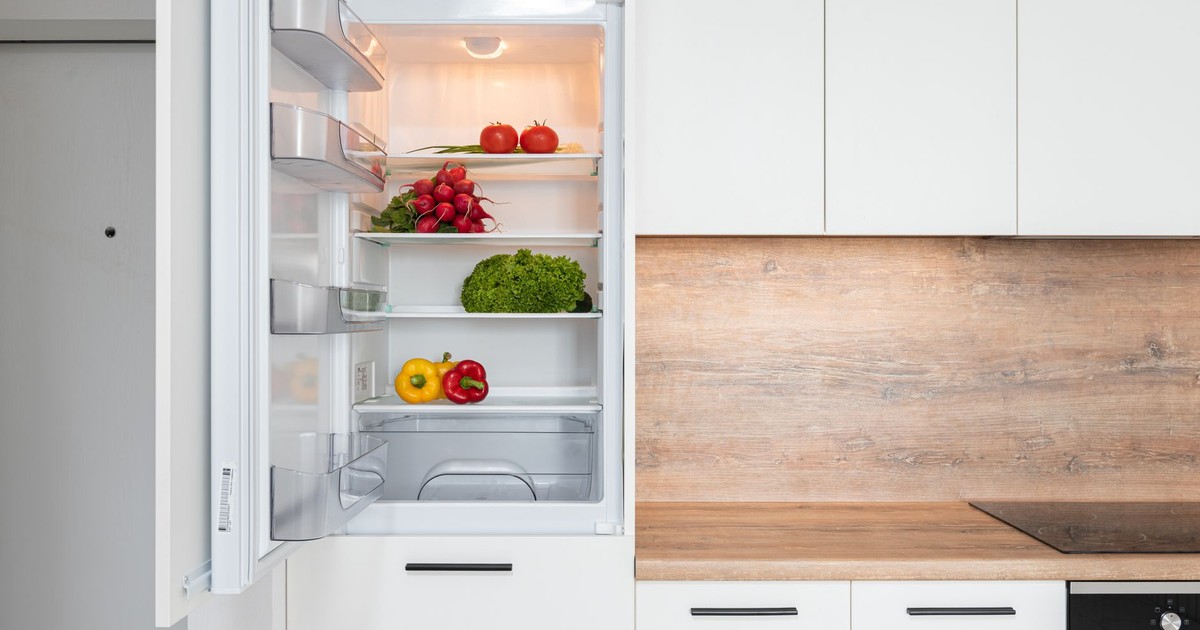 Contemporary kitchen with refrigerator filled with fresh bright tomatoes lettuce and bell peppers