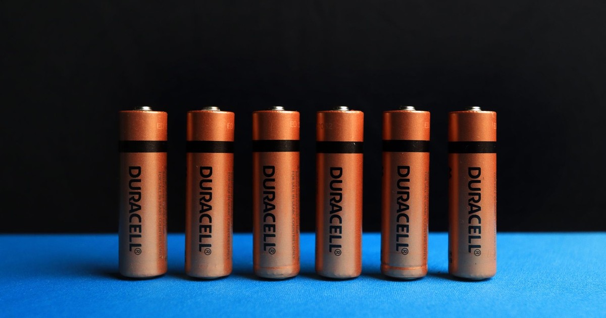 A lined up set of AA batteries with black and blue background.