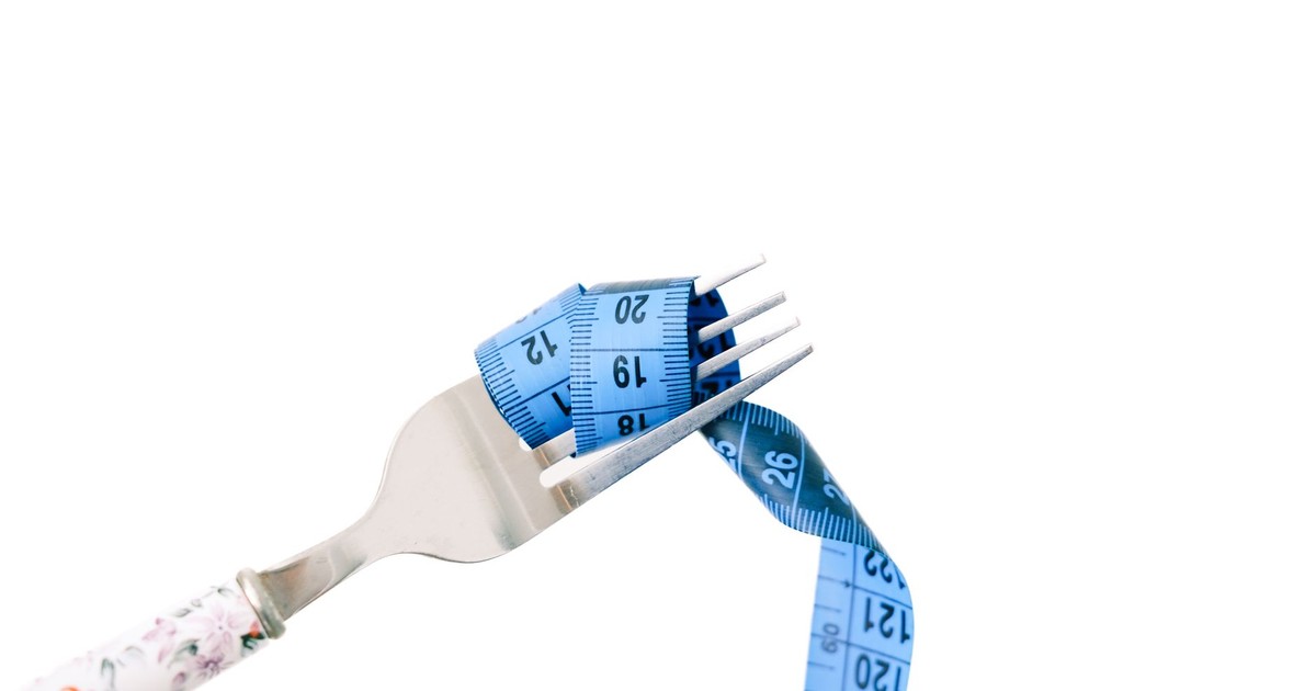 A fork entwined with a blue measuring tape, symbolizing dieting and weight management.