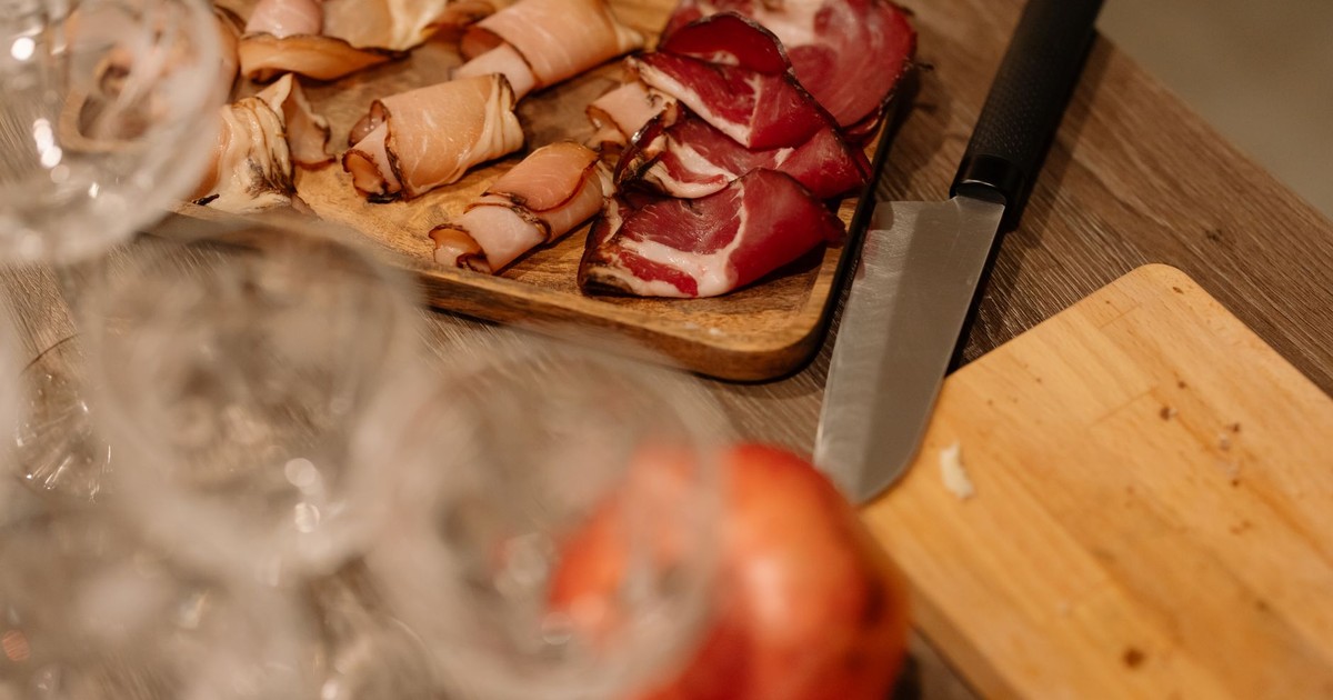 Close-up of sliced meats on a wooden tray with a knife, perfect for food blogs.