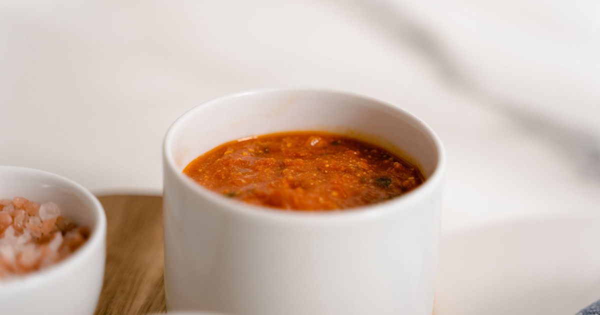 A close-up of rich marinara sauce in a white ceramic cup, perfect for pasta dishes.