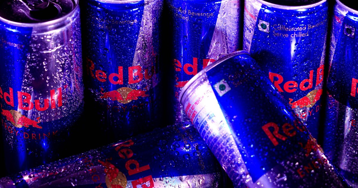 Close-up of multiple Red Bull cans with water droplets, highlighting freshness and energy.