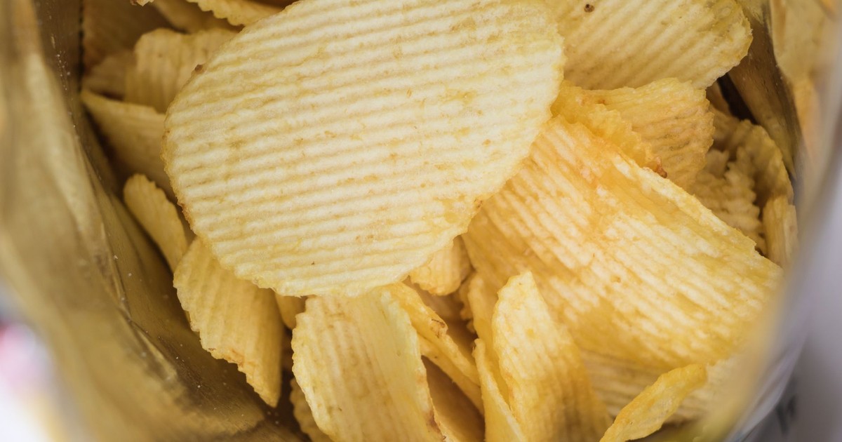 A detailed look at crispy ridged potato chips in an open snack bag, highlighting flavor and texture.