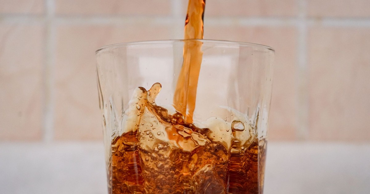 Close-up view of cola being poured into a glass with a splash effect, showcasing refreshing texture.