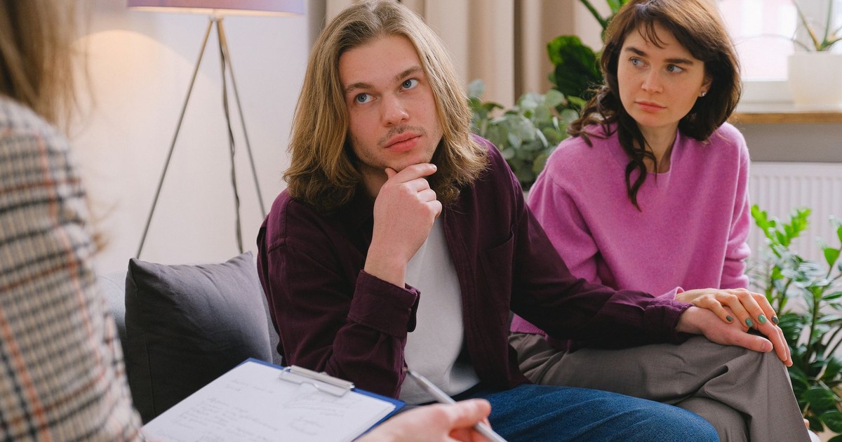 A couple holding hands during a therapy session in an office setting.