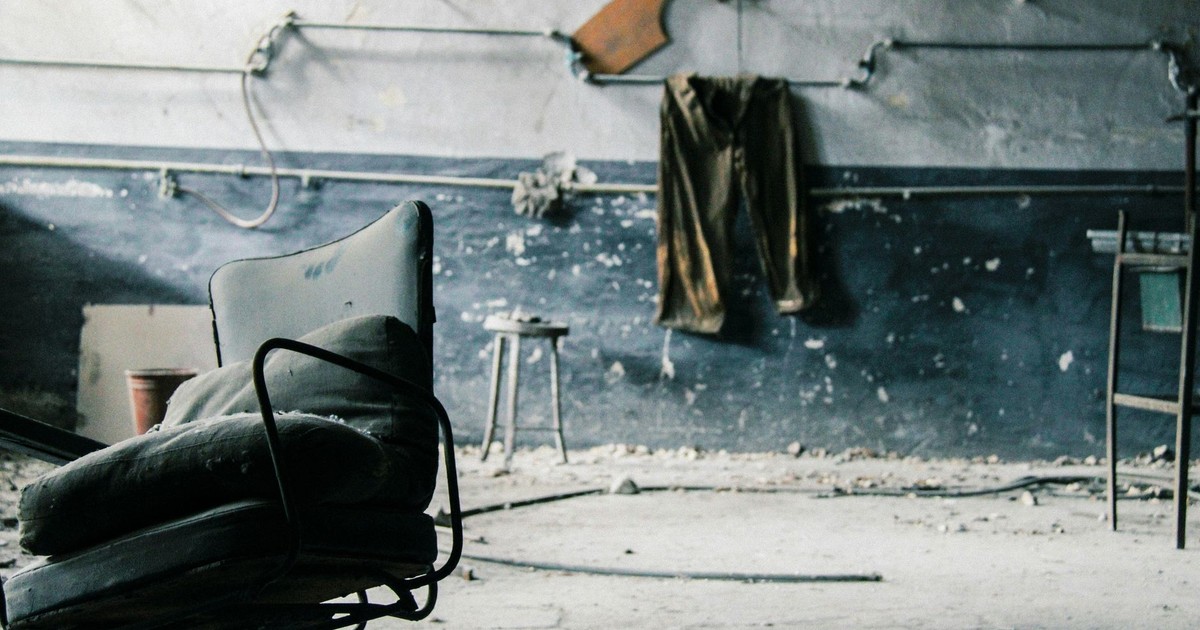 Dusty chair in a deserted room with peeling walls and industrial decor. Captures urban decay.