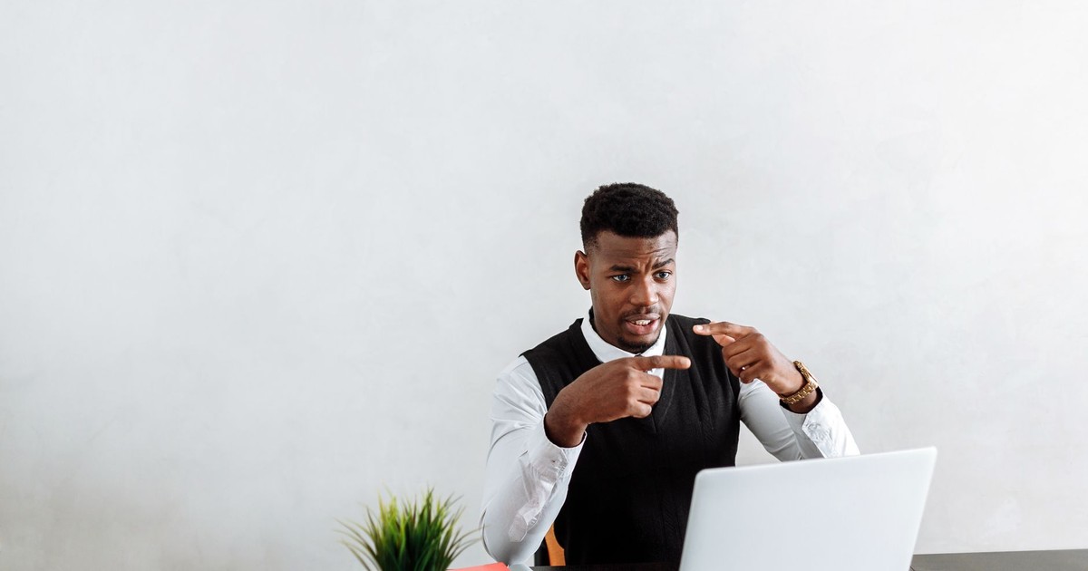 Professional businessman explaining during video call using laptop in modern office setting.