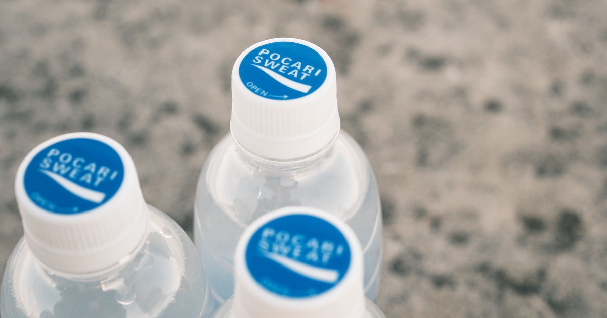 Three Pocari Sweat bottles on a stone surface, focus on blue caps.