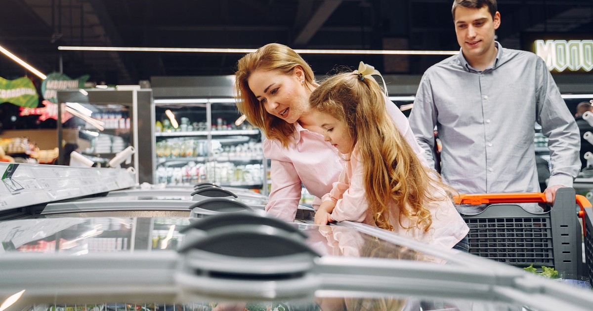 A happy family shopping in the supermarket's freezer section, emphasizing togetherness and love.