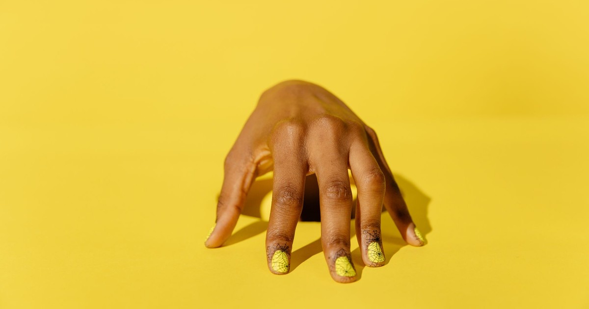 Stylish yellow nail art on a hand against a vibrant yellow background, perfect for beauty and fashion themes.