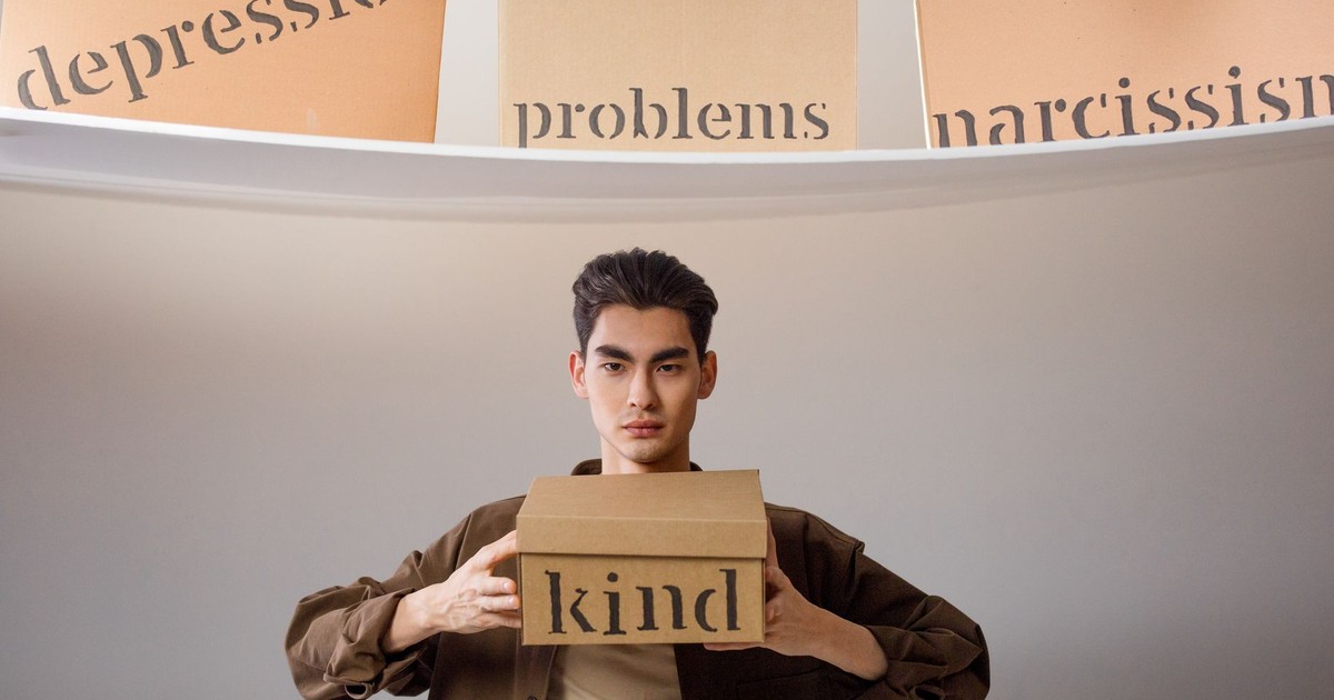 Creative image depicting a person balancing emotional concepts represented on cardboard boxes.