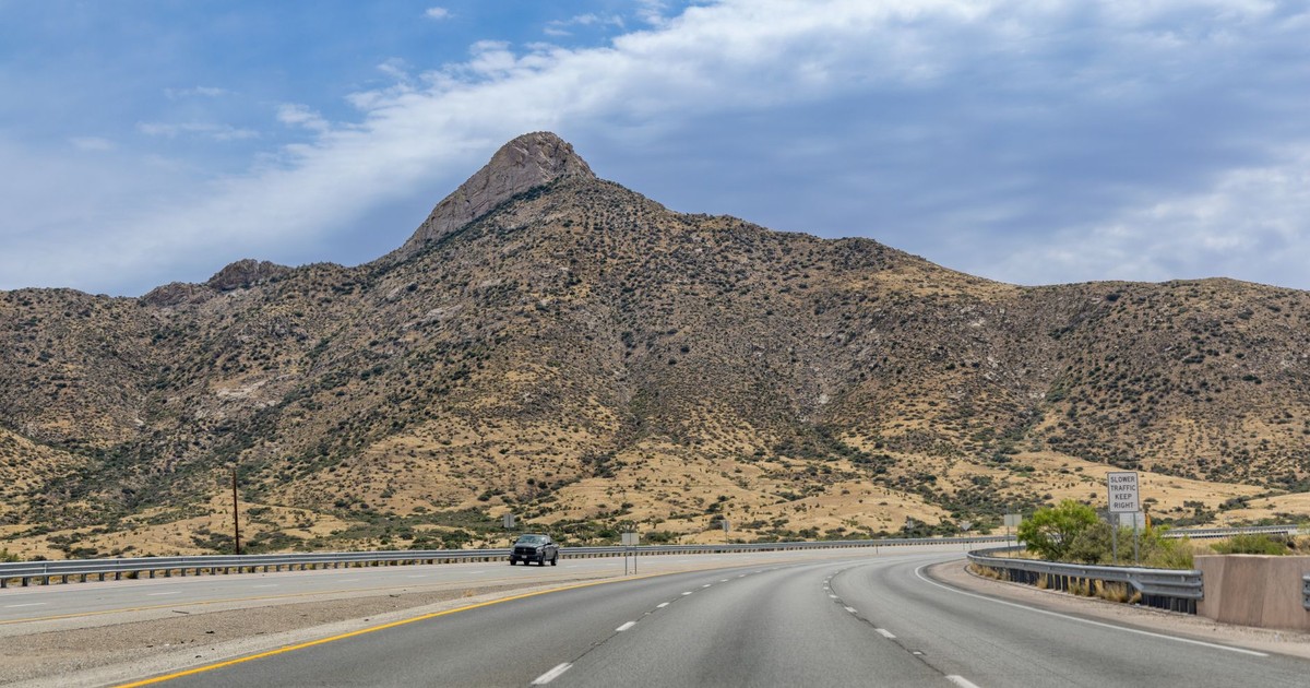 Desert highway leading to rugged hills under a clear sky in El Paso, Texas.