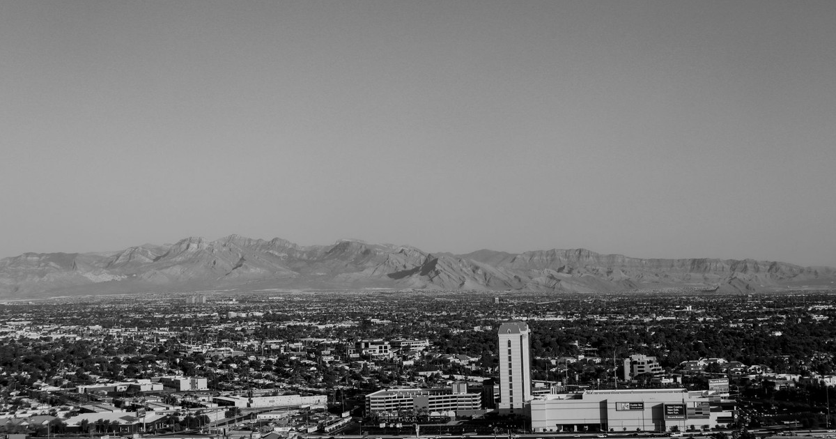 Black and white aerial shot of Las Vegas cityscape with mountains.