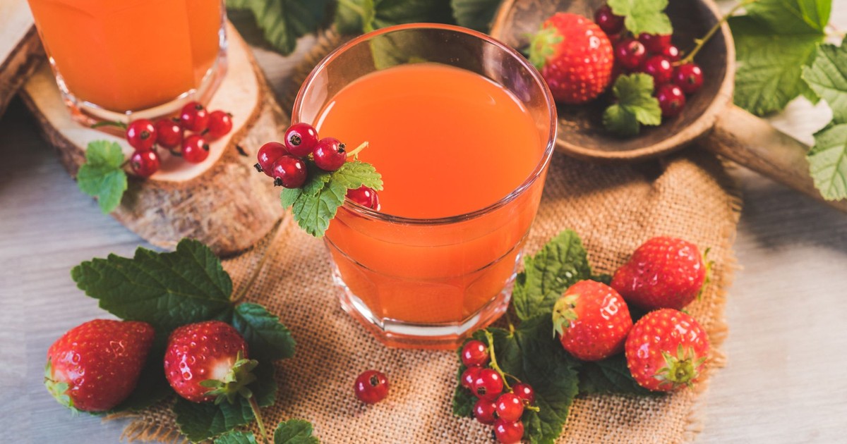 A refreshing glass of berry juice surrounded by fresh strawberries and red currants. Perfect for a healthy lifestyle.
