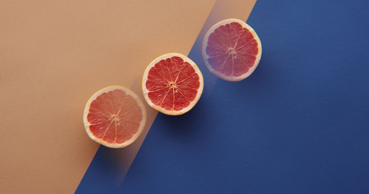Artistic top view of grapefruit slices on contrasting orange and blue background
