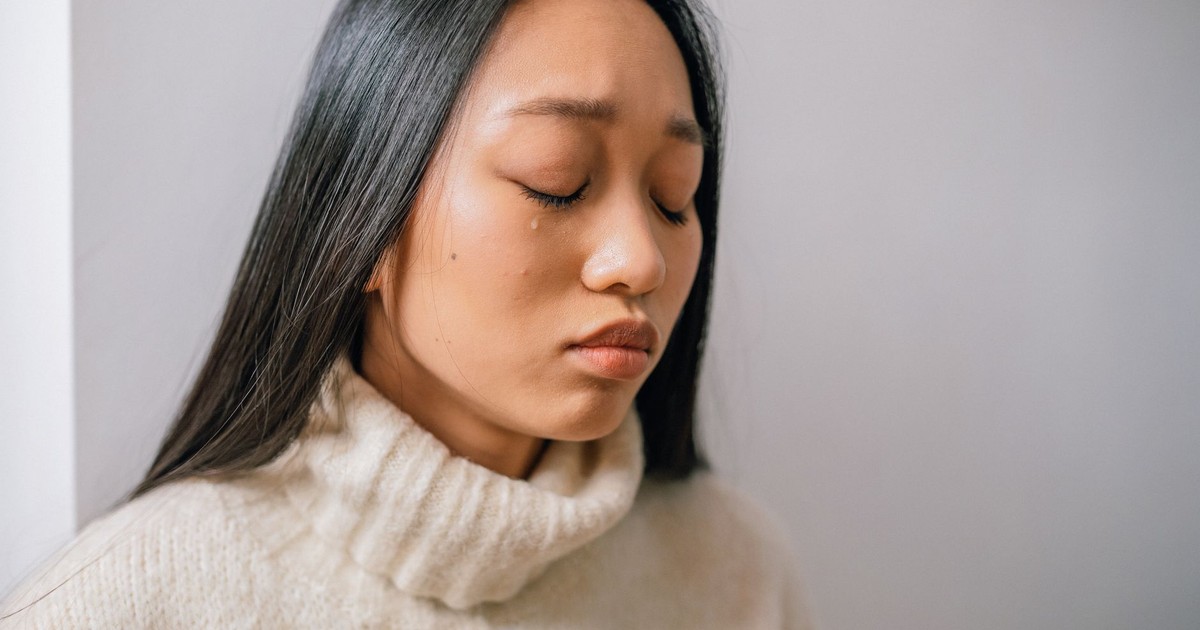 Close-up of an Asian woman with tears, showcasing emotional depth and sadness.
