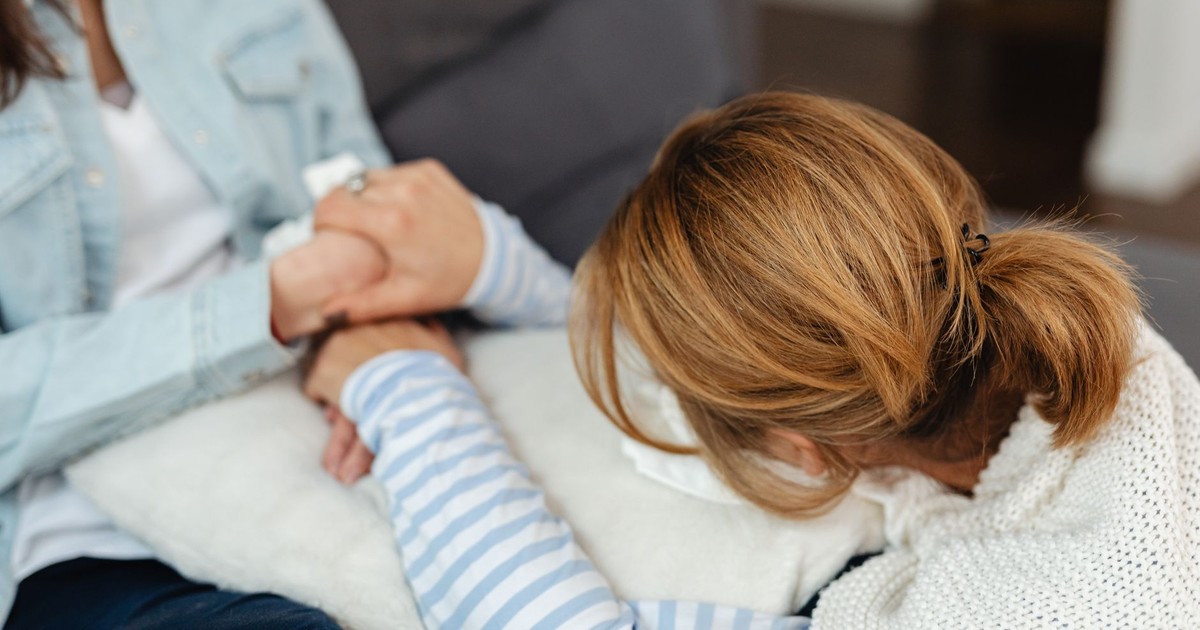 Two women share a comforting moment, emphasizing support and empathy in emotional distress.