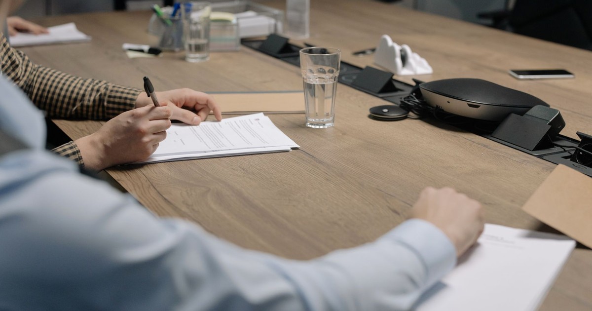 Professional setting of a business meeting with individuals signing documents on a conference table.