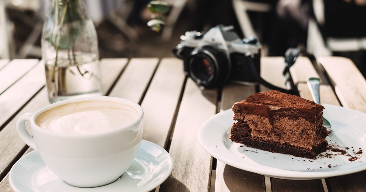 A delightful scene featuring a cappuccino and chocolate cake on a sunny outdoor table, perfect for a cozy break.