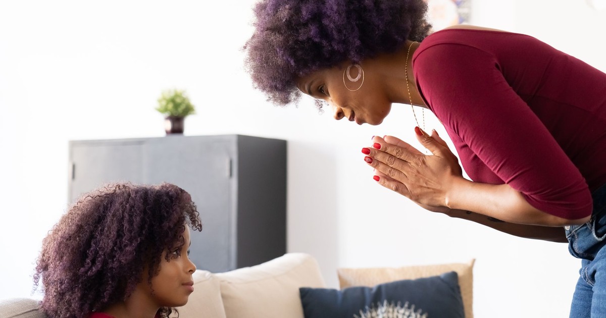 A touching moment between a mother and her daughter indoors, emphasizing family bonds.