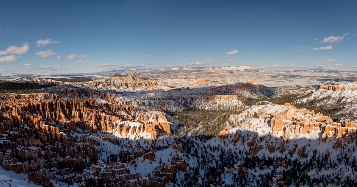Stunning panoramic view of Bryce Canyon in winter with snow-covered hoodoos and clear blue skies.