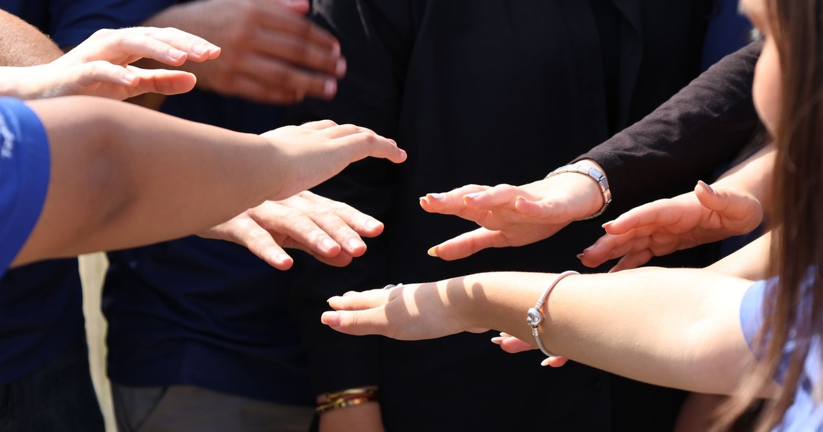 A diverse group of people placing hands together symbolizing teamwork and unity.