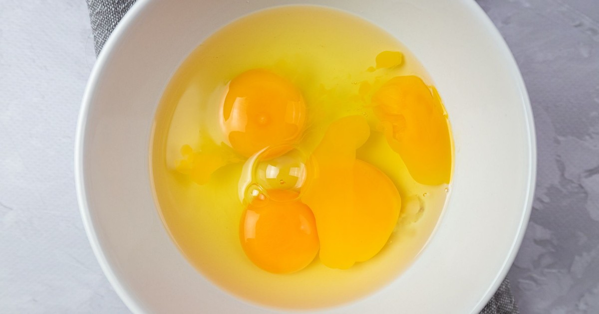 Top view of fresh raw egg yolks in a white ceramic bowl, perfect for cooking or baking concepts.