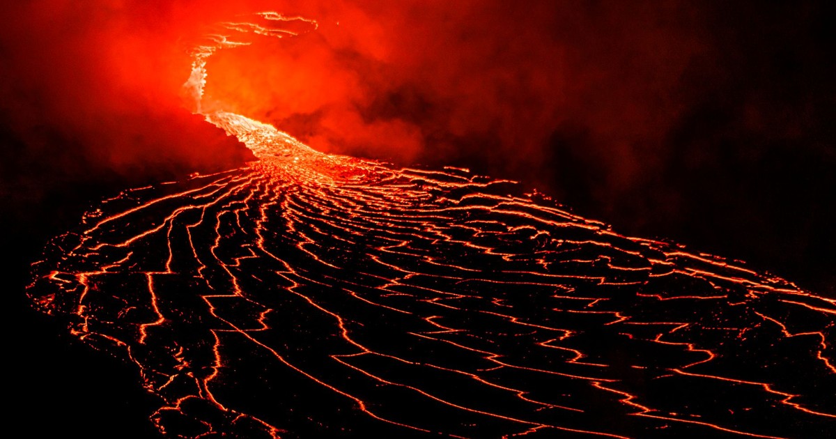 Spectacular lava flow from an erupting volcano under the night sky, showcasing fiery reds and intense heat.