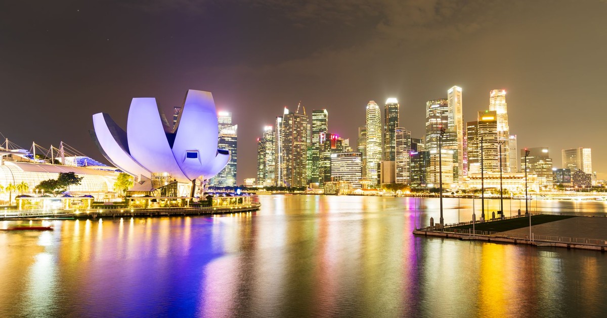 Night view of Singapore's illuminated skyline and Marina Bay Sands, reflecting vibrant city lights.
