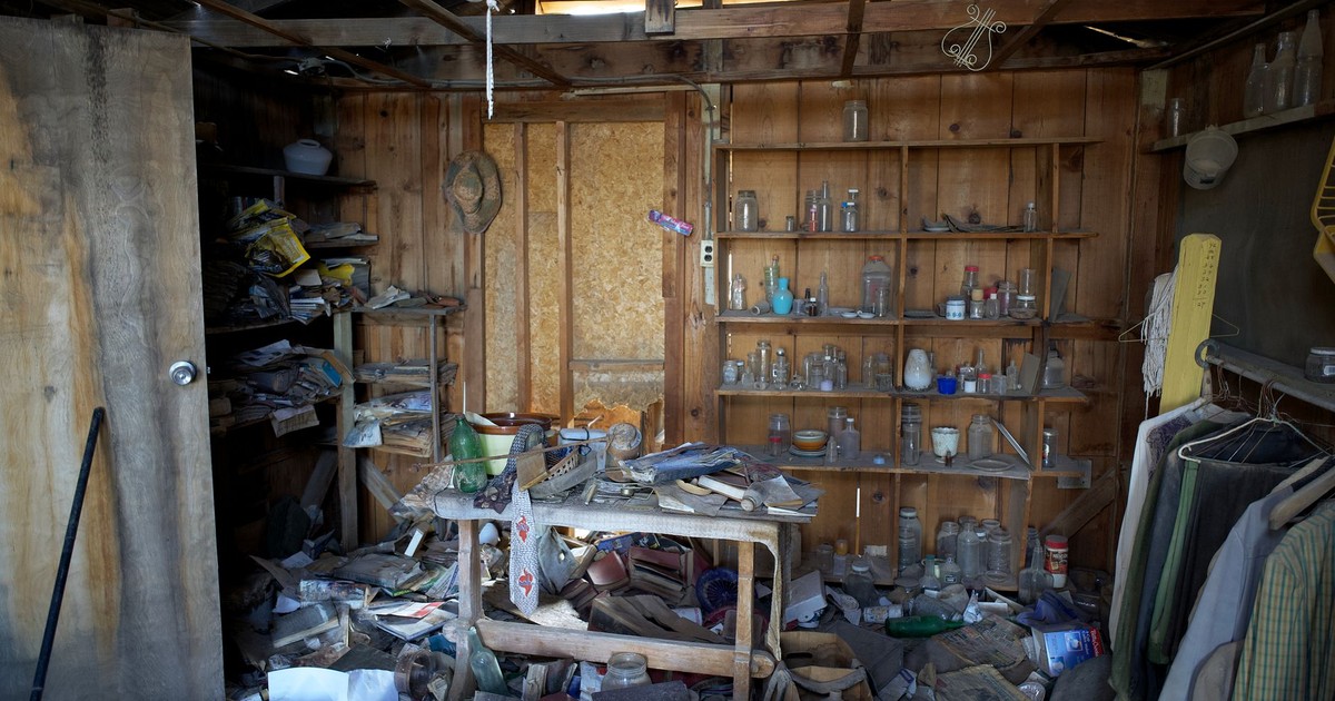 Interior view of an abandoned room filled with dusty and disorganized items, typical of urban decay.