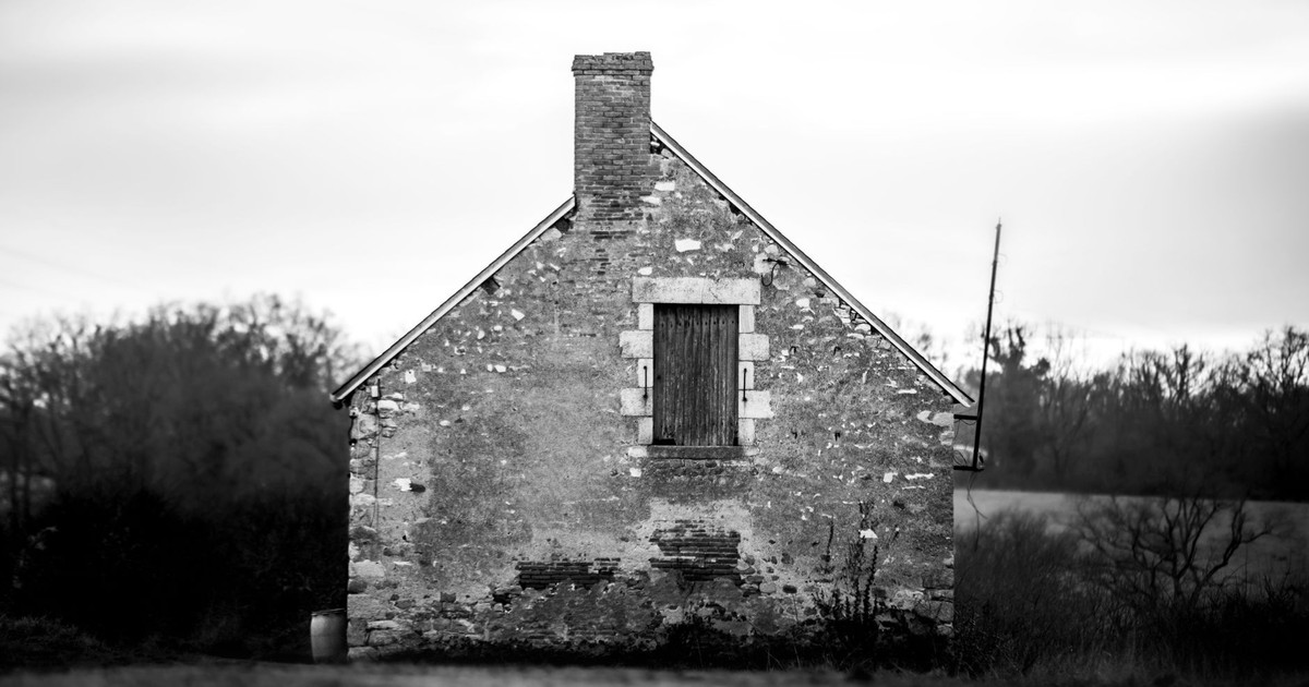 Black and white photo of an abandoned old French house in rural France, evoking historical charm.